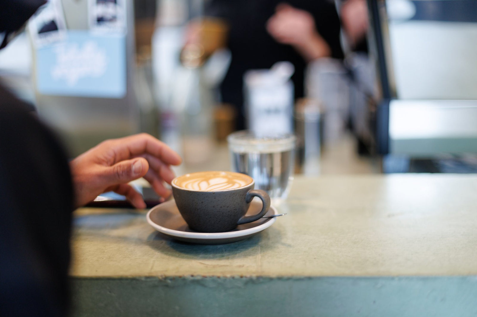 Een flat white wordt aangereikt aan de toog