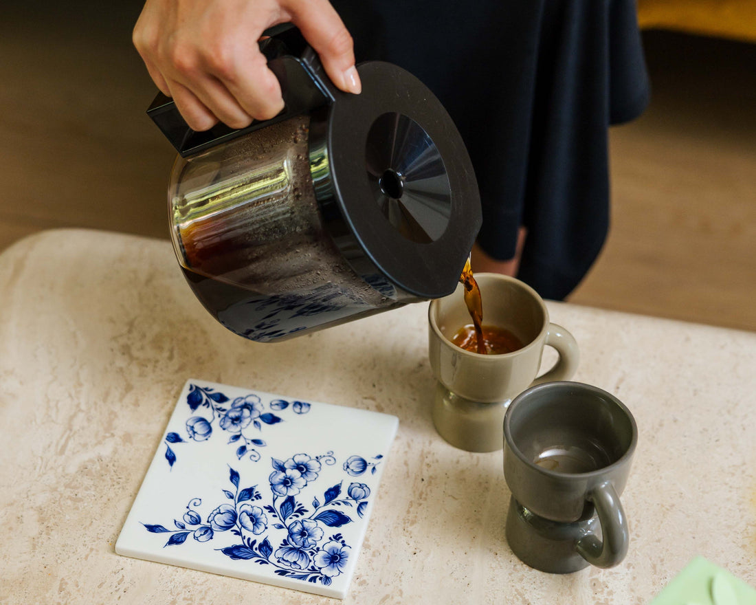 Verse filterkoffie wordt uit een kan in twee mokken geschonken
